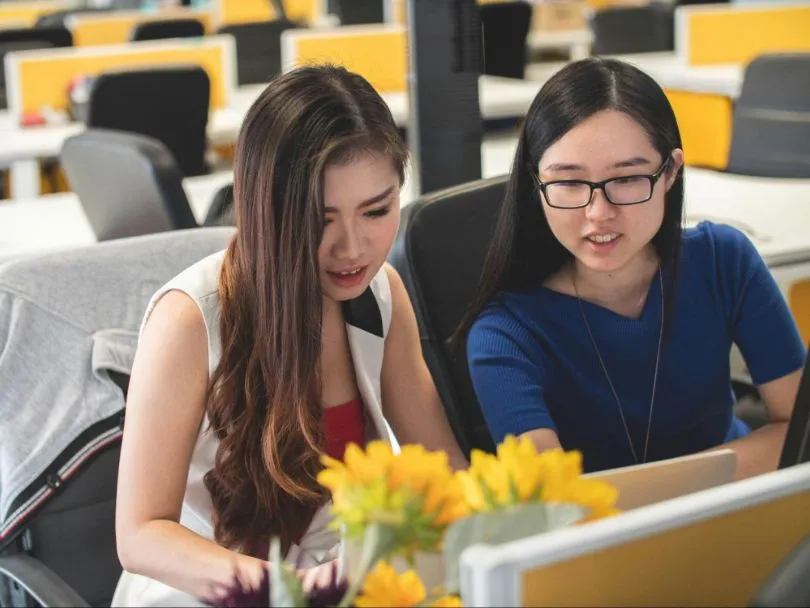 Two Asian women using recruitment automation on their computer for hiring