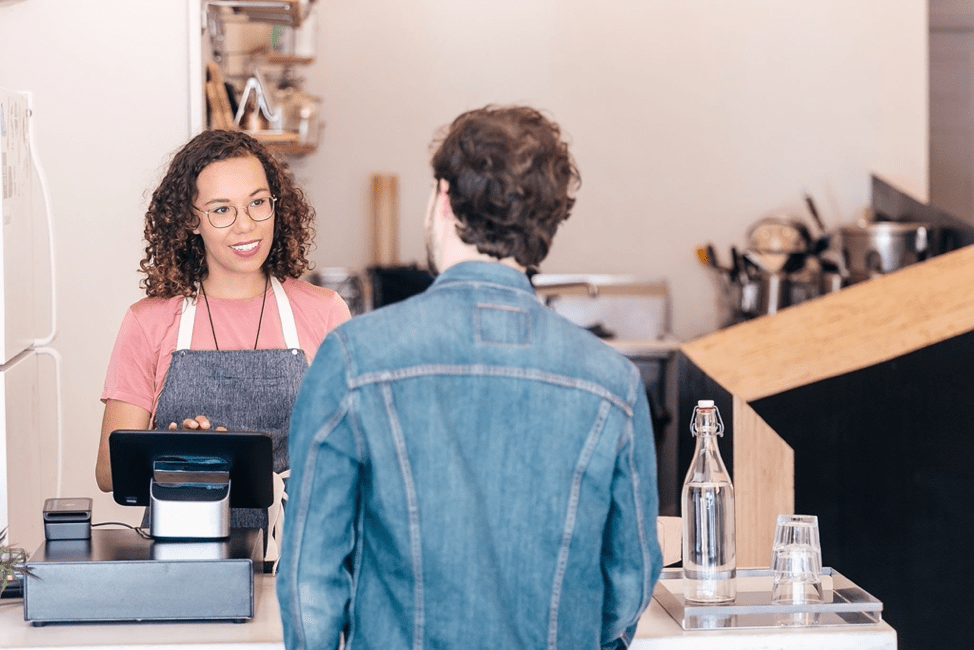 Female retail worker at the till serving a male customer