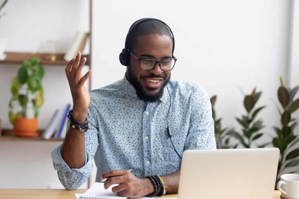 Smiling African American employee in headphones using laptop