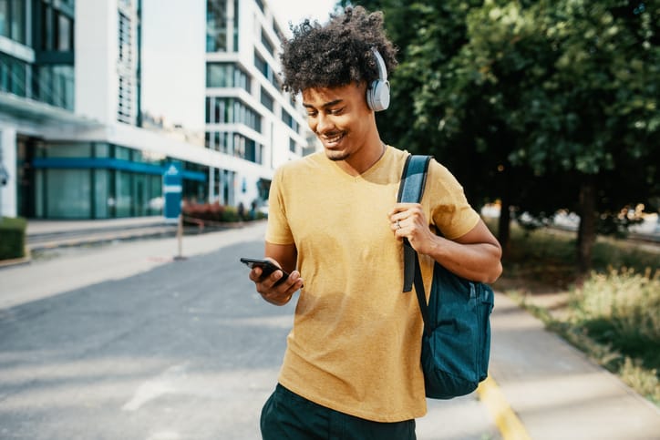 Photo of young mixed race male in downtown, going to work or back from work, drinking coffee, using public transport or sipping coffee