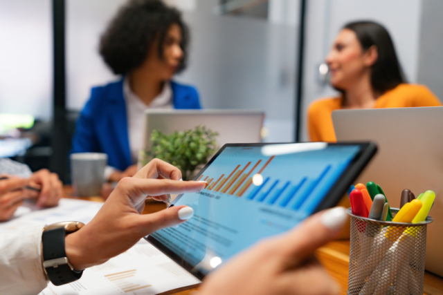 Close-up on a woman watching statistical graphs on a tablet in a business meeting